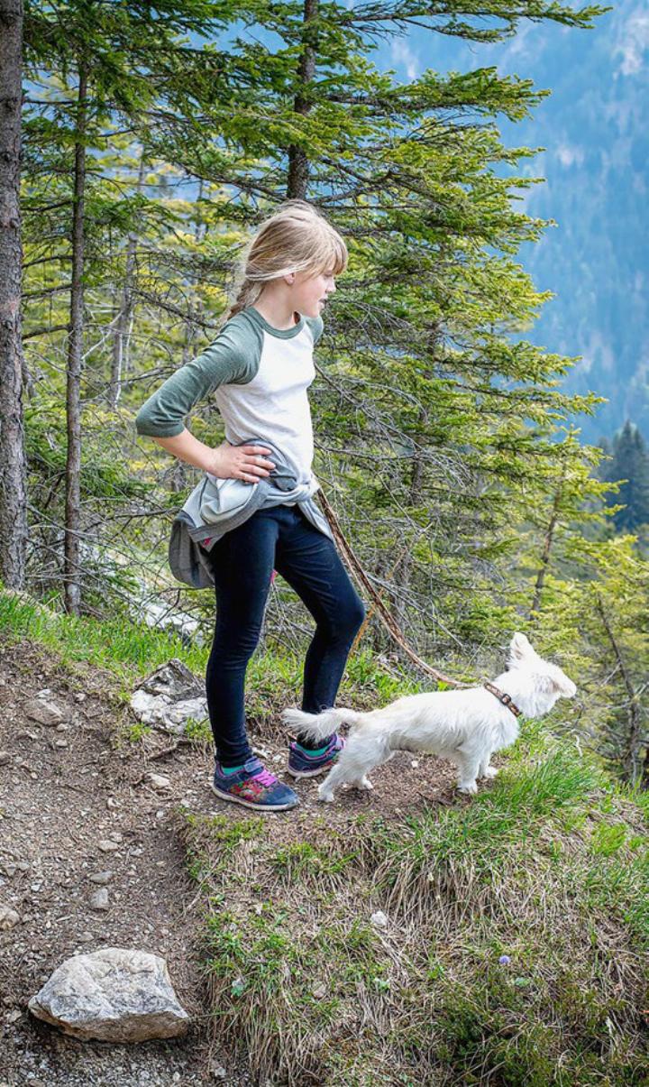 Gemeinsames Wandern, hier eine junge Frau mit ihrem Hund in den Bergen