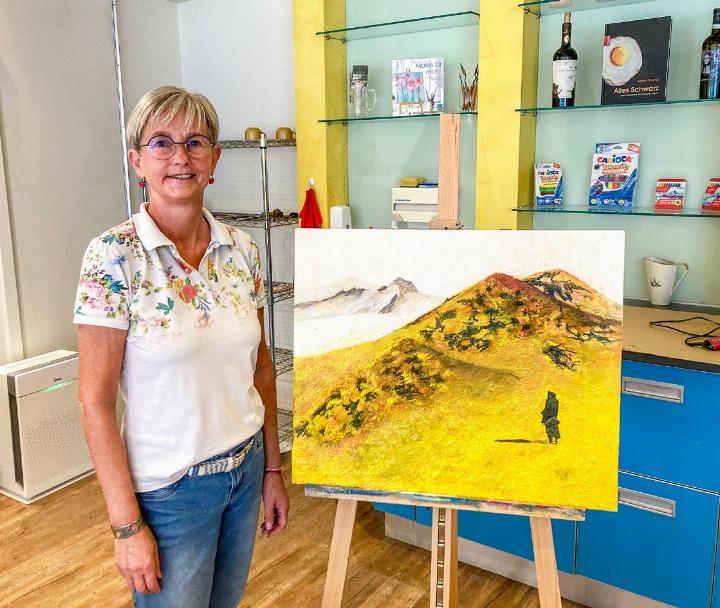 Gaby El Badri vor einem Gemälde, gefertigt mit Wüstensand unter der Acrylfarbe. BILD: RAHEL ROESTI