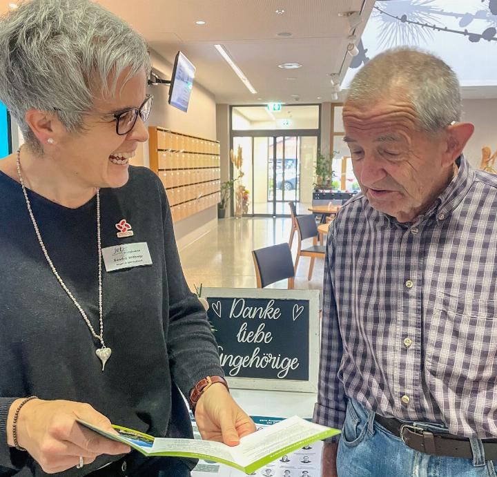 Am Angehörigentag im jetzt Fröschenmoos zeigt Sandra Wittwer am Informationstisch Peter Willen den neuen Flyer. BILD: RACHEL HONEGGER